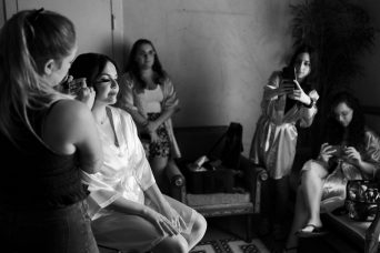 תמונה בגווני אפור ובה אישה שעוברת תהליך איפור וברגע נשים מצלמות אותה בטלפונים שונים