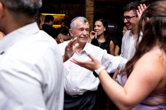תמונה ובה איש מבוגר לובש כיפה וחולצה לבנה רוקד